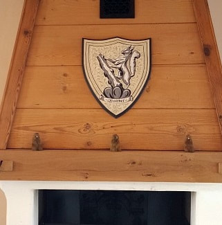 Family crest painting on traditional wall plaque ​ over fireplace